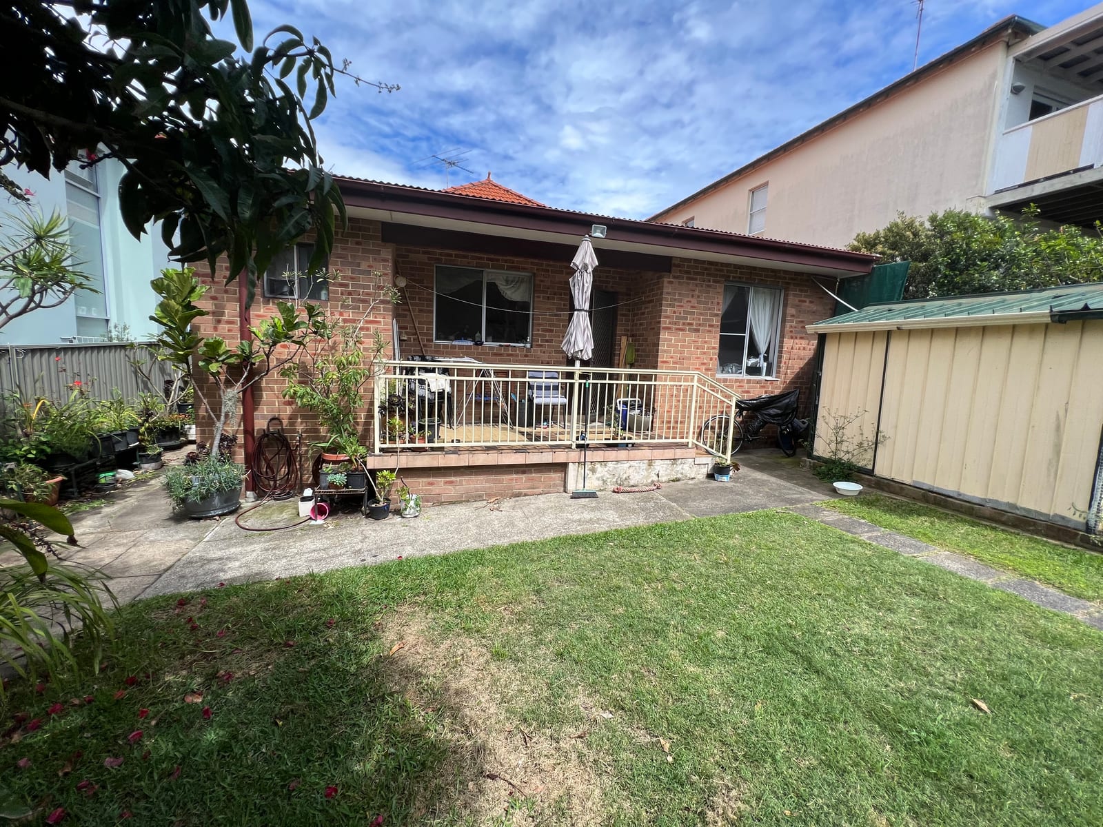 Before — The original single-storey rear yard before the renovation, and the same rear elevation after the home was taken up to two storeys with a new balcony