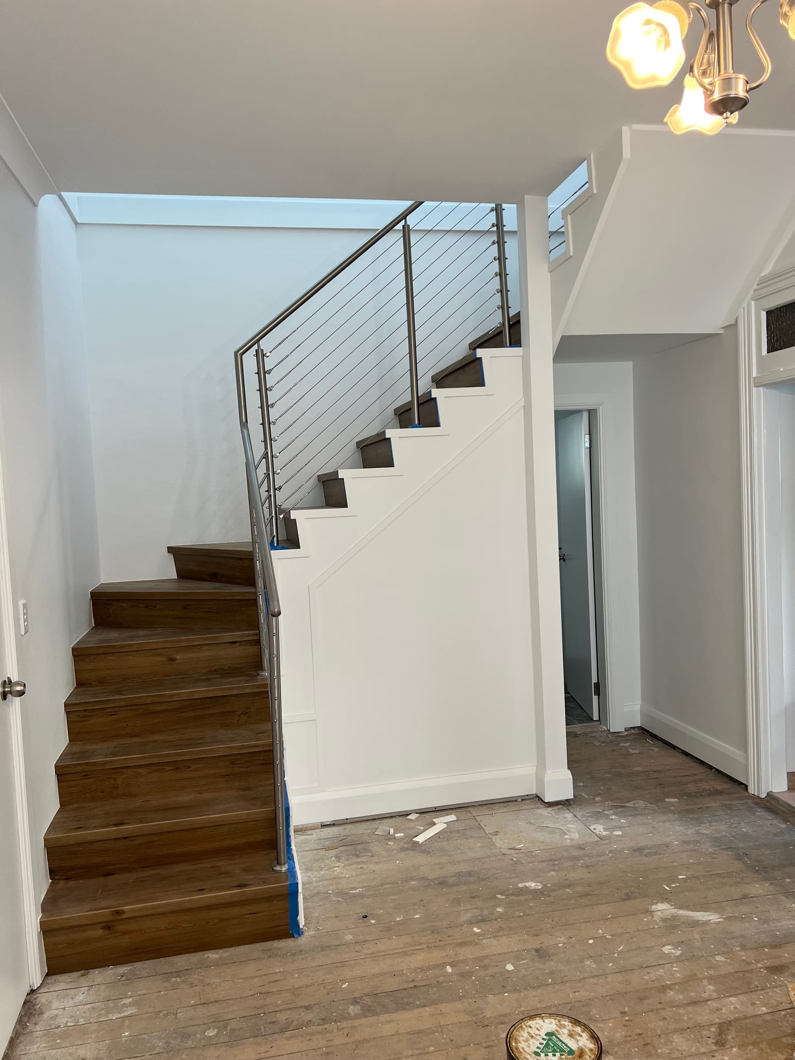 The new internal staircase — timber treads and a stainless cable-and-post balustrade, lit by a skylight above