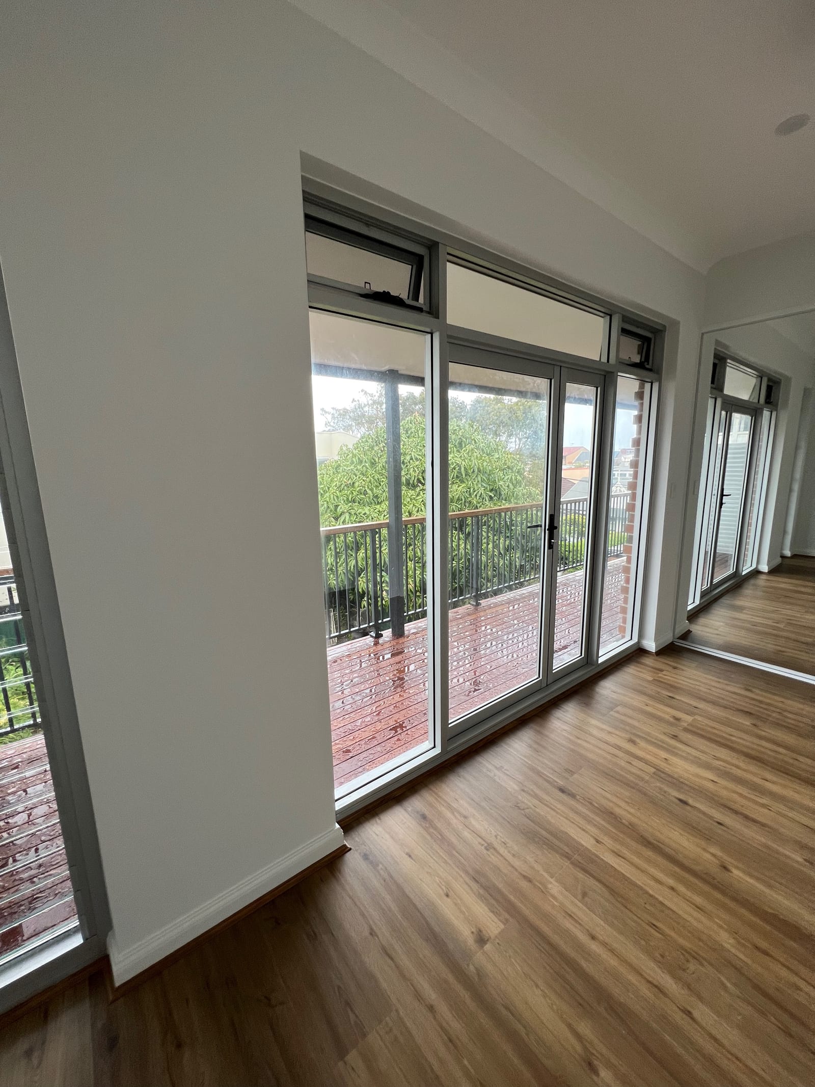 A finished upper-level room — timber-look flooring, a raked ceiling and full-height glazed doors to the balcony