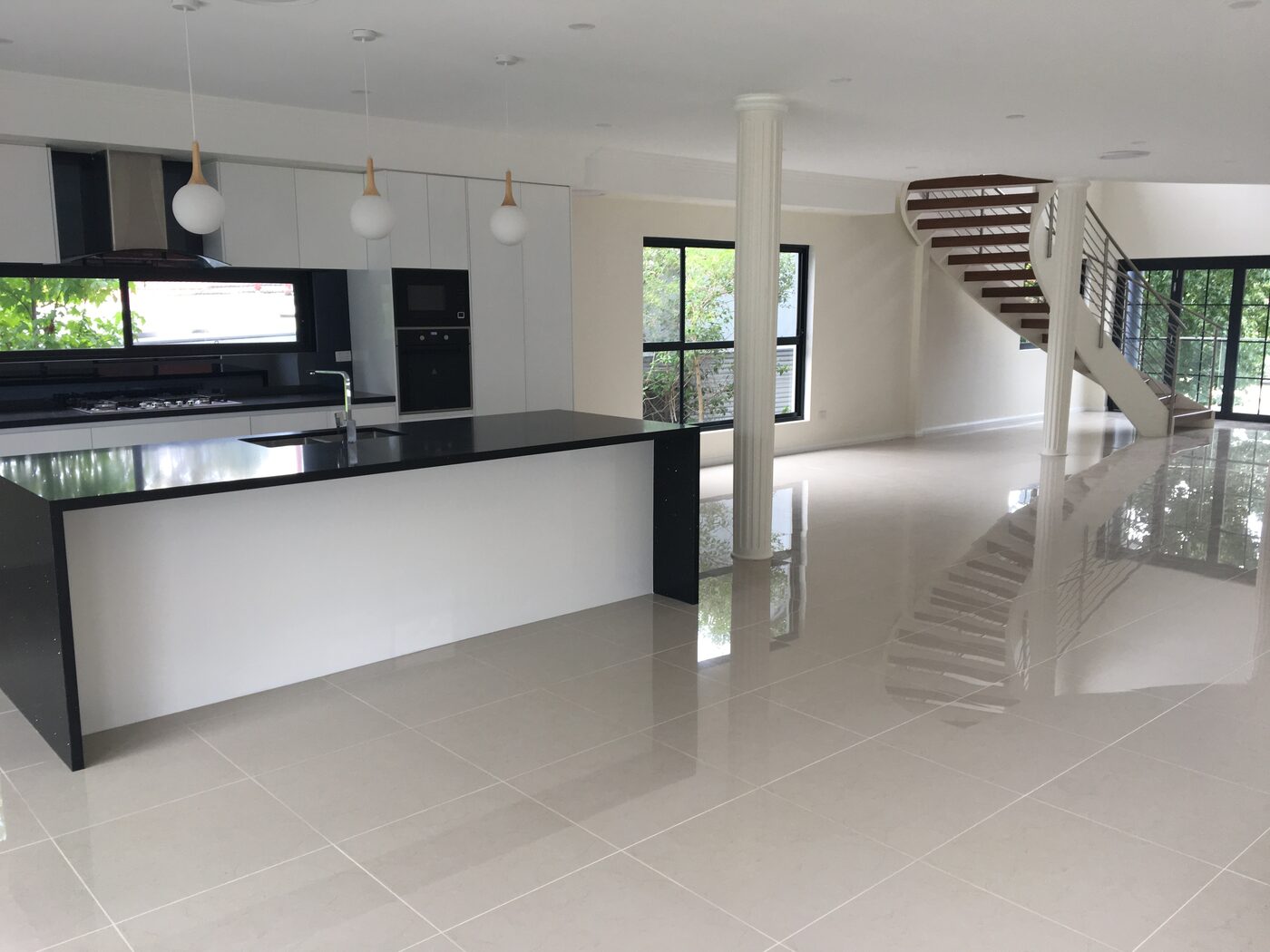 Open-plan kitchen with a waterfall-edge island, black stone benchtop and pendant lighting
