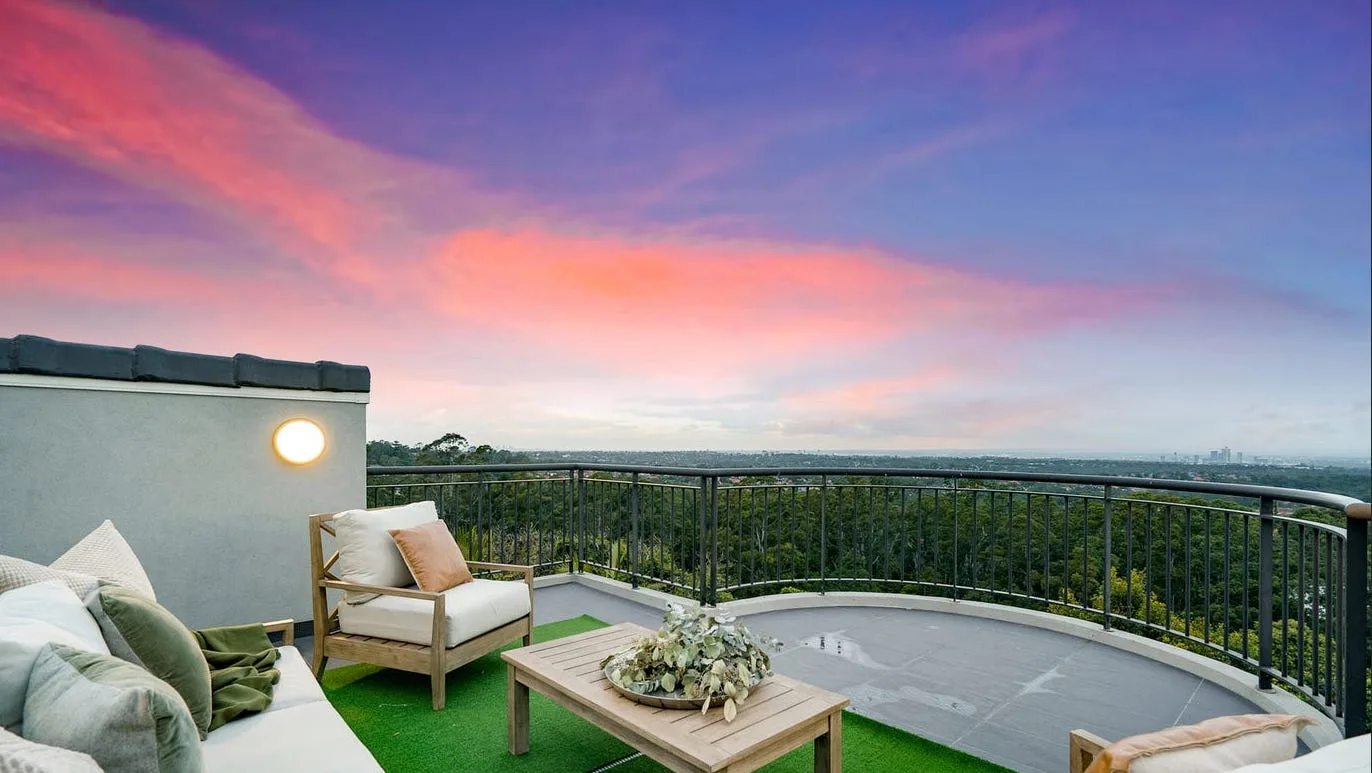 The rooftop terrace lounge at dusk, looking out to a distant view of the city skyline.