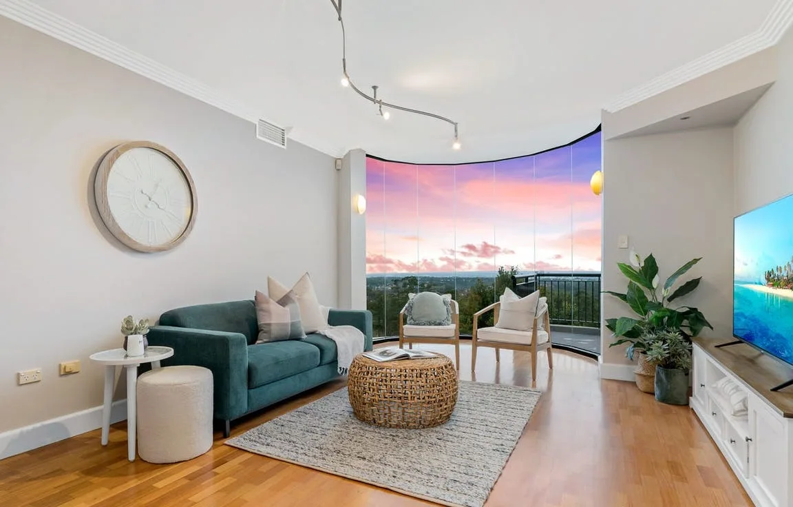 The curved-glass living room at dusk, styled with furniture.