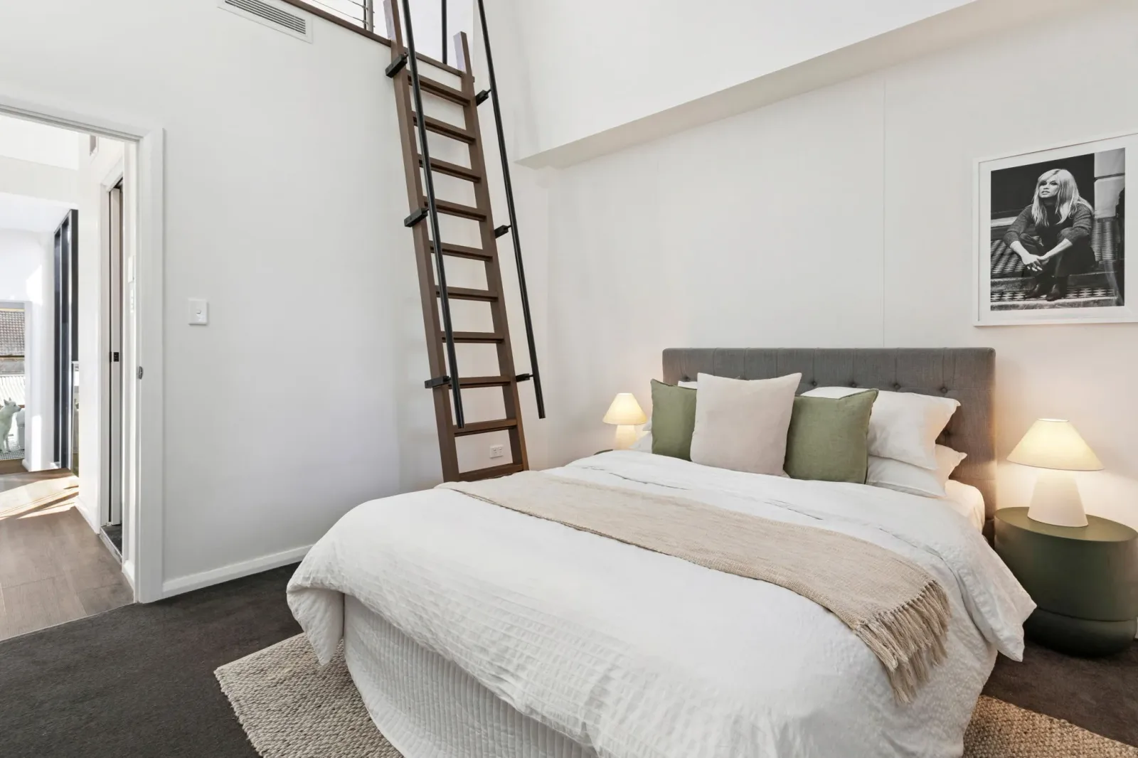 A bedroom with a raised ceiling and a timber ladder leading to a loft storage space above the wardrobe.