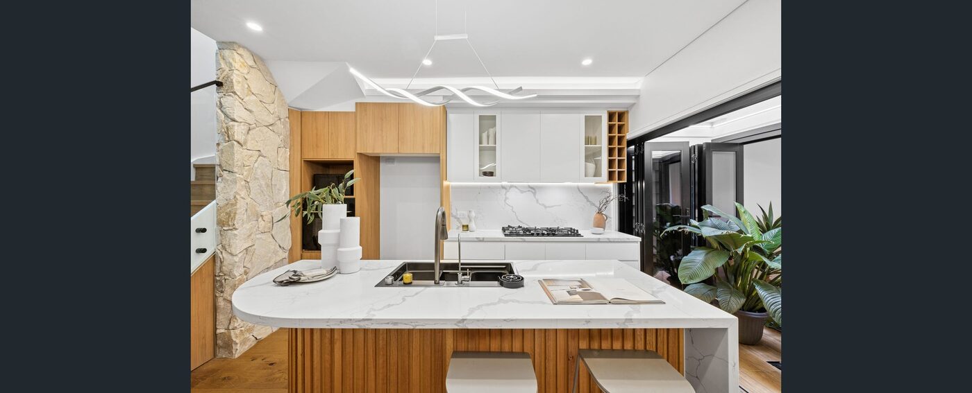 The finished kitchen — timber and white joinery with a stone island
