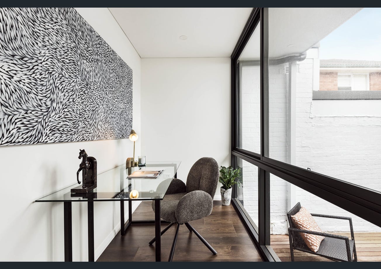A study nook with a built-in glass-top desk beside a full-height window