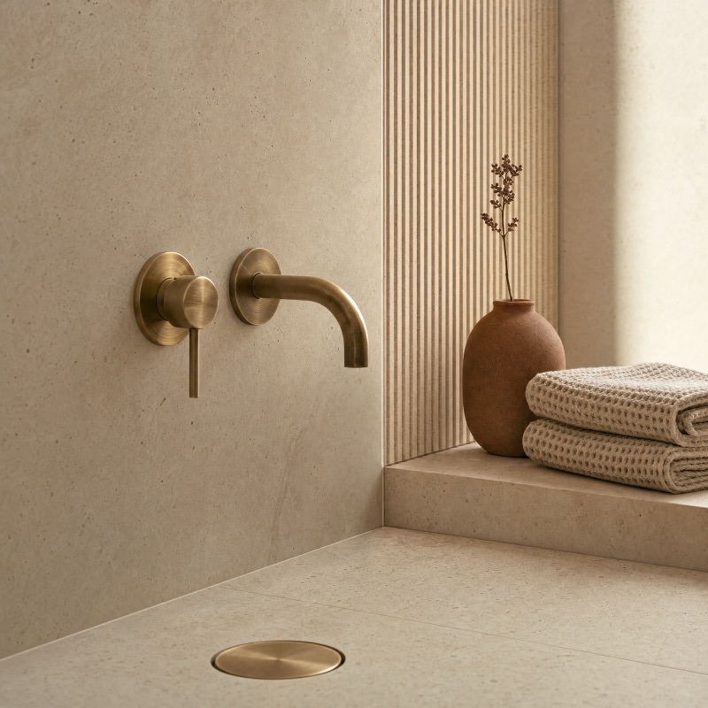 Brushed brass tapware against honed travertine — Panadium detail work