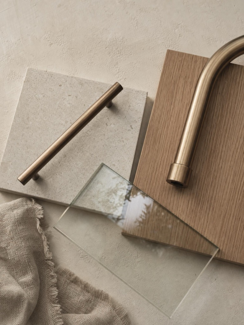 New-home material selections — honed stone, oak veneer, brushed bronze and glass — illustrative concept